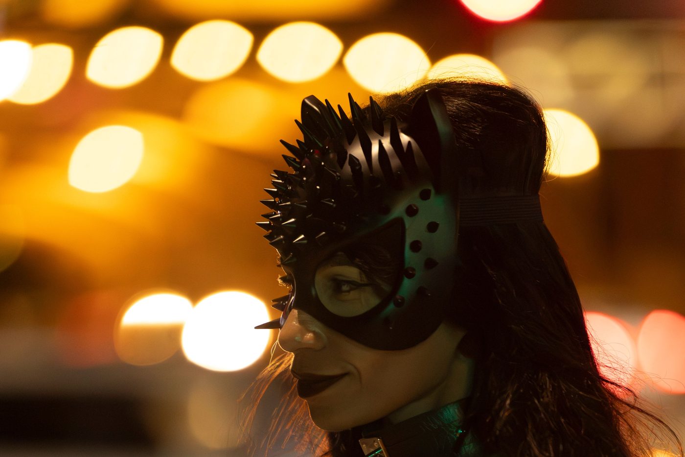 Mujer con máscara de gato y luces nocturnas de ciudad