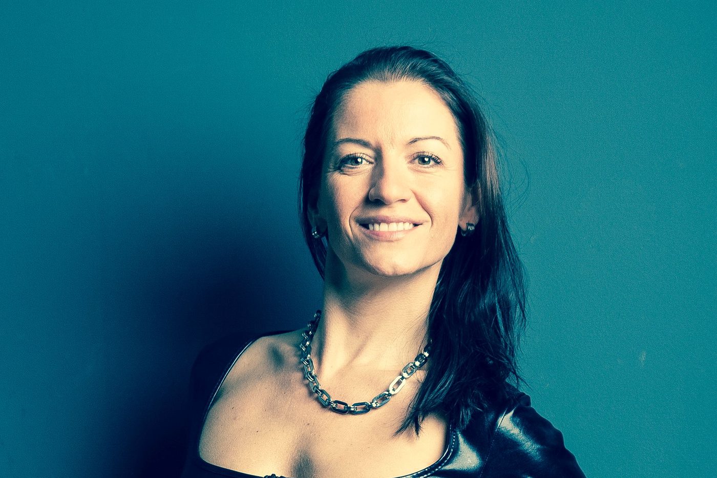 Mujer sonriente con vestido de látex negro sobre fondo azul