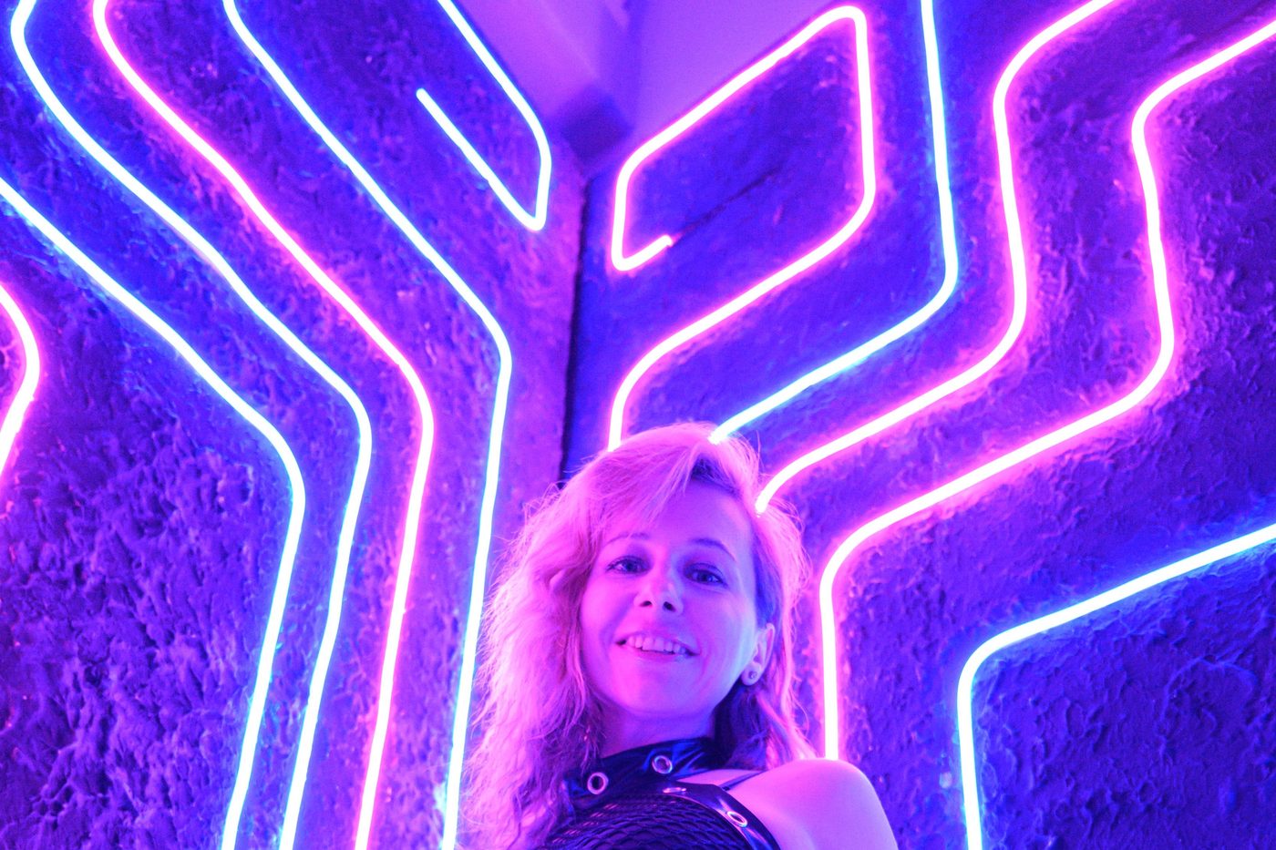 Mujer con conjunto fetiche bajo luces de neón violeta